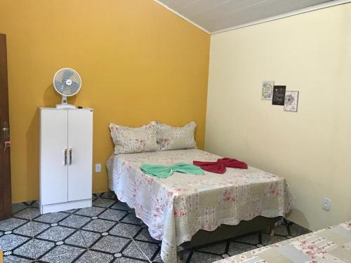 a small bedroom with a bed and a fan at Suite Raio de Sol in Vale do Capao