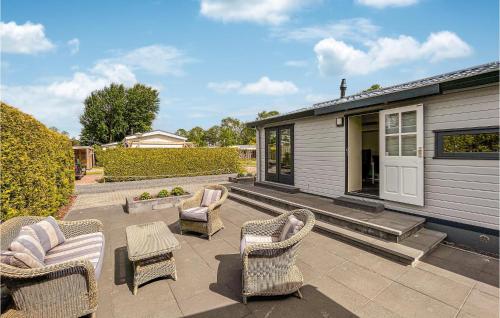 eine Terrasse mit Stühlen, einem Tisch und einem Haus in der Unterkunft Amazing Stacaravan In Tzummarum in Tzummarum