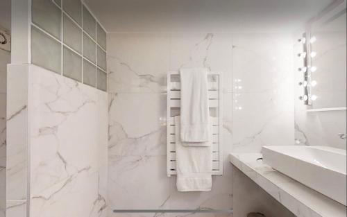 La salle de bains blanche est pourvue d'un lavabo et d'un porte-serviettes. dans l'établissement Loft HeartofParis, Marais,Chatelet, Beaubourg CLIM, à Paris