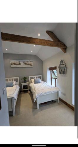 a bedroom with two beds and a ceiling with beams at Sunset cottage in Burry Port