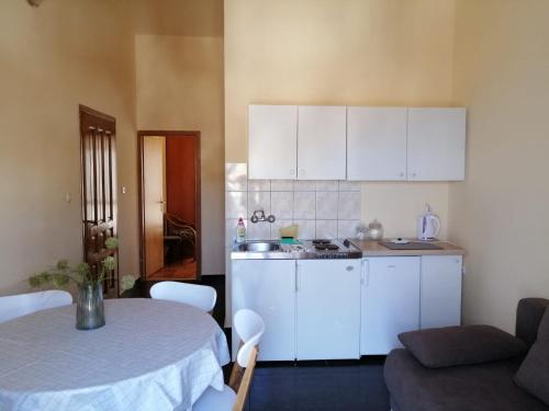 una cocina con armarios blancos y una mesa en una habitación en Apartmani Meštrović, en Drage