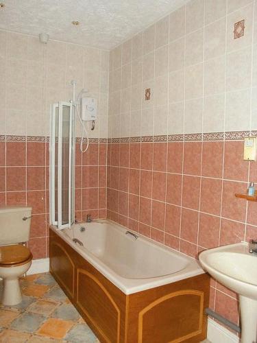 a bathroom with a tub and a toilet and a sink at The Grange Hotel in Kings Lynn