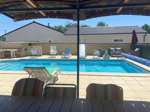 a swimming pool with a table and chairs next to it at Esprit Etape in Saint-Barthélemy-de-Vals
