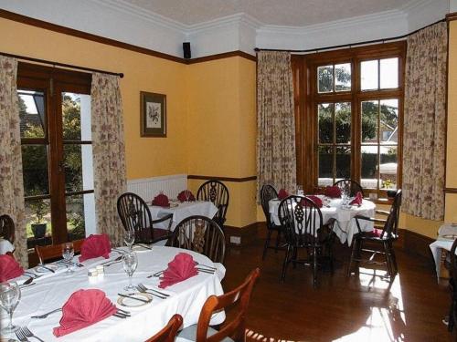 a restaurant with white tables and chairs and windows at The Grange Hotel in Kings Lynn
