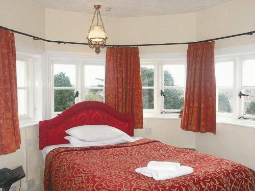 a bedroom with a red bed with two towels on it at The Grange Hotel in King's Lynn