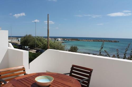 a wooden table and chairs on a balcony with the ocean at Casa fronte mare a Torre Vado 2 in Torre Vado