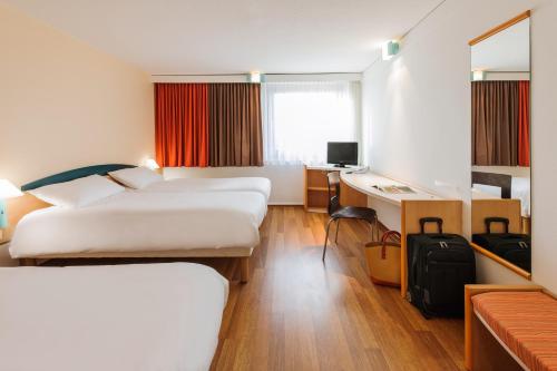 a hotel room with two beds and a desk at ibis Berlin Messe in Berlin