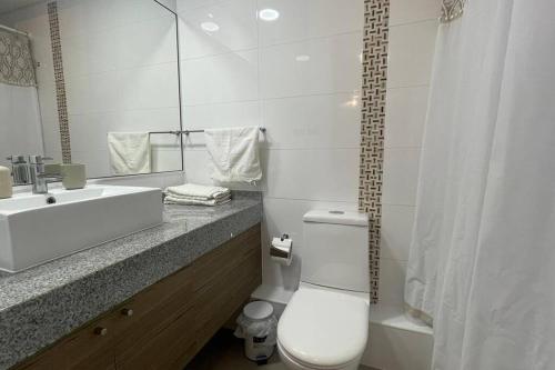 a white bathroom with a toilet and a sink at Hermoso departamento en la Península en Iquique in Iquique