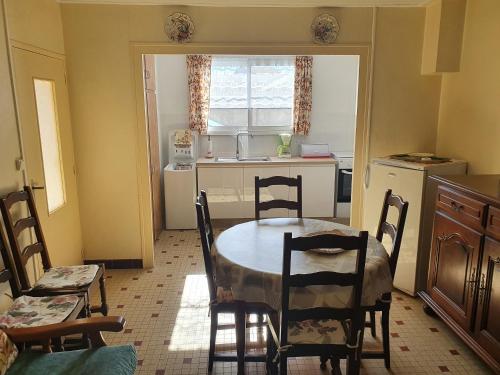 a kitchen with a table and chairs in a room at MAISON DE VACANCES in Saint-Vincent-sur-Jard