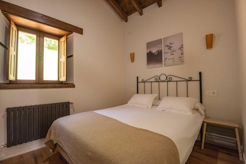 1 dormitorio con 1 cama con sábanas blancas y ventana en Apartamentos Rurales Playas De Niembro, en Llanes