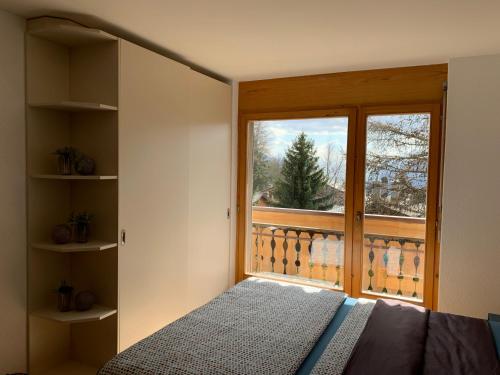 1 dormitorio con cama y ventana grande en Apartment Number 8 en Crans-Montana