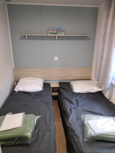 deux lits dans une petite pièce avec une fenêtre dans l'établissement Mobil-home Narbonne-Plage, à Narbonne-Plage