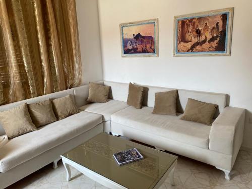 a living room with two white couches and a coffee table at Dar Ezzahra in Tozeur