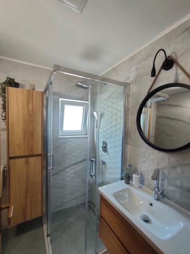 a bathroom with a shower and a sink and a mirror at Baška Voda - Apartmani Vesna in Baška Voda