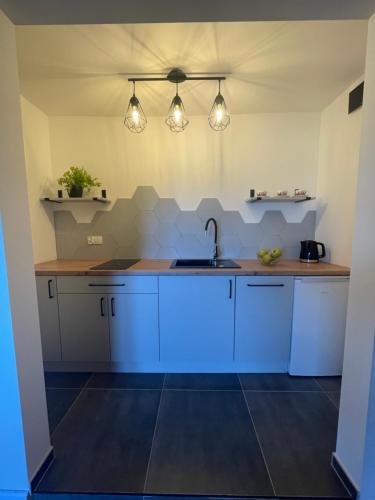 una cucina con armadi bianchi, lavandino e luci di Pokoje Gościnne u Hanki a Bukowina Tatrzańska