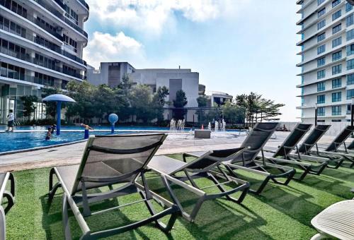 a row of lawn chairs sitting next to a pool at 1410Encorp/Bathtud/Netflix/100mbps/Legoland By STAY in Nusajaya
