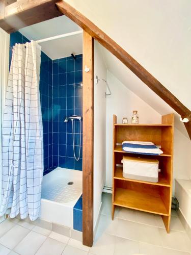 La salle de bains est pourvue d'une douche et d'une baignoire carrelée de bleu. dans l'établissement Toutes voiles dehors - Vue mer & château - Cosy, à Dieppe