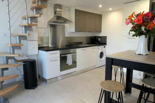une cuisine avec des placards blancs et une table avec un vase de fleurs dans l'établissement VILLA CAREMEAU 2, à Nîmes