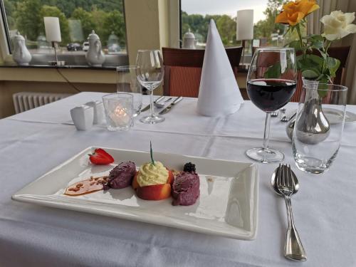 a plate of desserts on a table with wine glasses at Hotel Haus am See in Simmerath