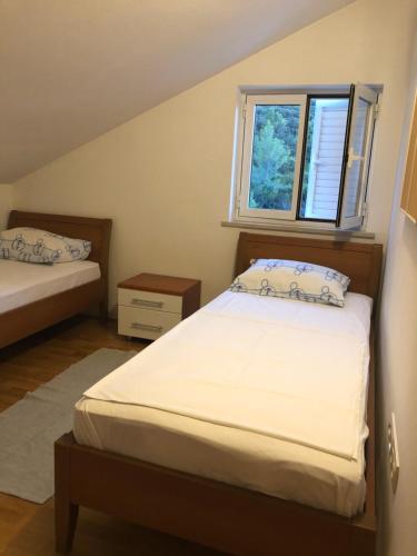 a bedroom with two beds and a window at Apartmani Luka in Korčula