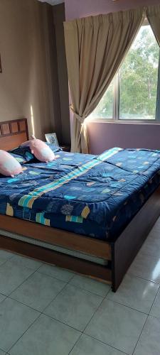 a bedroom with a bed with a blue comforter and a window at Cosy Laketown Service Apartment in Kampong Selemat