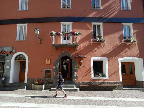 a man walking in front of a building at Hotel Gufo in Bormio