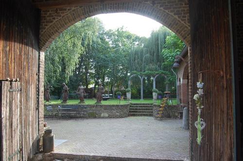 an archway leading into a park with statues in the background at Col du Fatten in Beek