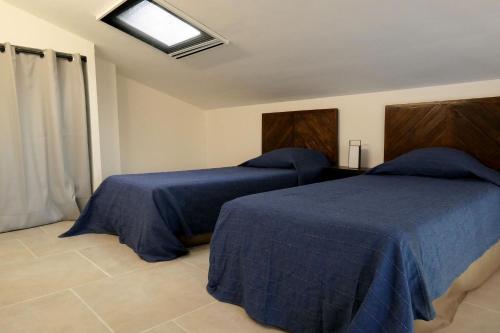 a bedroom with two beds with blue sheets and a window at VILLA CAREMEAU 2 in Nîmes