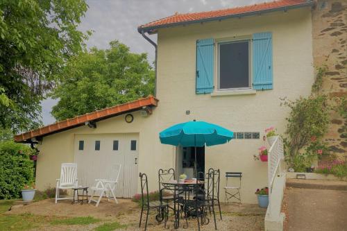 une table avec un parasol devant une maison dans l'établissement La Belle Vue - Coin de paradis, à Sussac