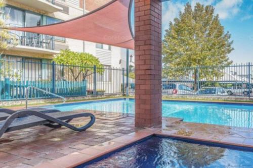 a swimming pool with a bench next to a building at SUBI CENTRAL CLOSE CBD HOSPITALS WIFI NETFLIX WINE in Perth