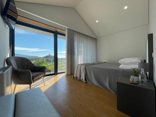 una camera da letto con un letto, una sedia e una finestra di Casa das Branquinhas - Férias no Minho com piscina! a Ponte de Lima