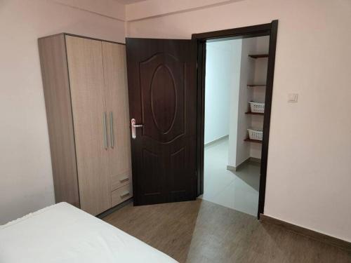 a bedroom with a wooden door and a closet at 28A, Apt#13 Lumir Apartamentos. Encantador Parque Incl. in Luanda