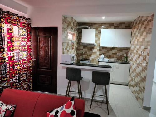 a kitchen with a red couch and two stools in a room at 28A, Apt#13 Lumir Apartamentos. Encantador Parque Incl. in Luanda