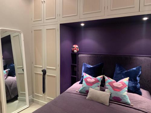 um quarto com paredes roxas e uma cama com almofadas em Charming and full of character em Londres