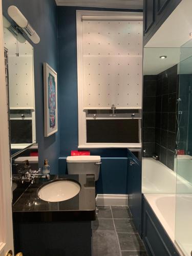 een badkamer met een toilet, een wastafel en een bad bij Charming and full of character in Londen