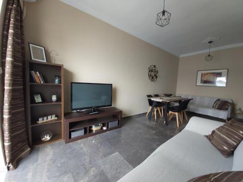 a living room with a couch and a tv and a table at Orion front sea apartment in Theologos