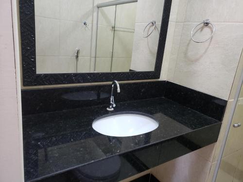 a bathroom with a sink and a mirror at Enseada Suítes in Guarapari