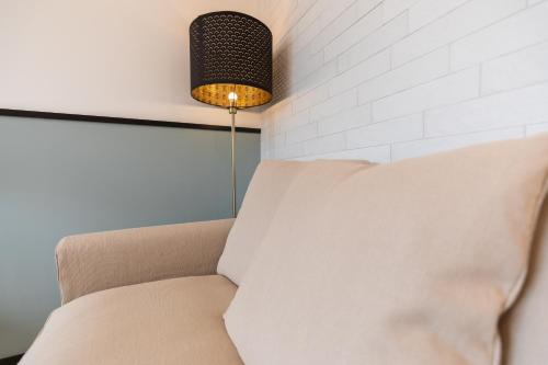 a couch sitting next to a wall with a lamp at Antares Rooms and Suites in Olbia