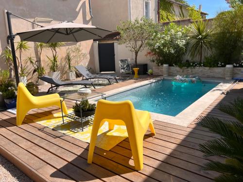 - une piscine avec 2 chaises jaunes et un parasol dans l'établissement Cosy Studio en Provence, à Carpentras