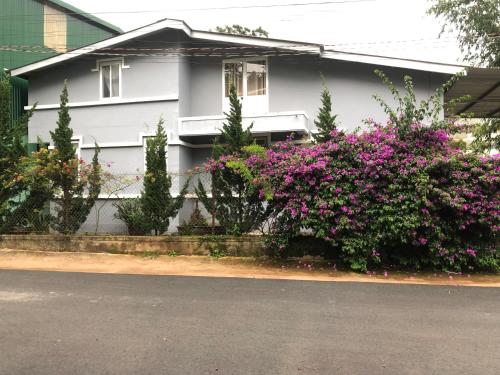 a white house with pink flowers in front of it at Bắp's House Đà Lạt in Da Lat