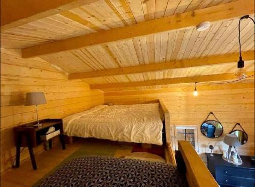 a bedroom with a bed in a log cabin at Cabane Pomme de pin in Le Porge