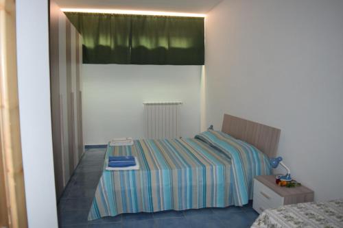 1 dormitorio con 1 cama con sábanas a rayas en Nel Verde per Mare e Terme, en Guardia Piemontese Terme