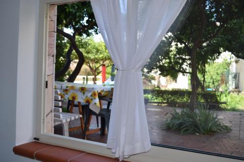 una ventana con una mesa con una cortina blanca en Nel Verde per Mare e Terme, en Guardia Piemontese Terme