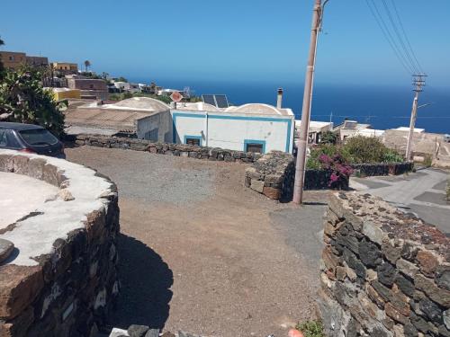 una calle con una pared de piedra y un edificio azul en La casa dei nonni, en Pantelleria