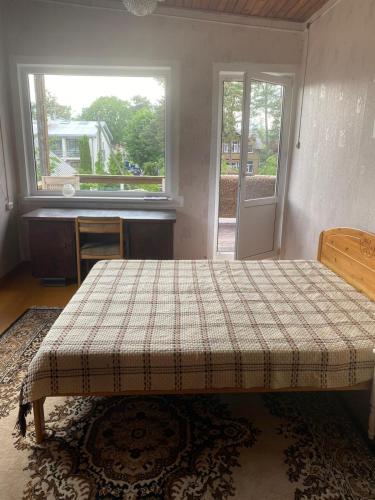 a bedroom with a bed and a desk and a window at The Dacha apartment in Jūrmala