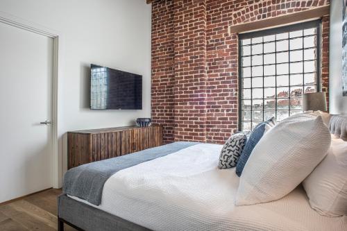 a bedroom with a brick wall and a bed with pillows at Elevation Lofts Hotel in Asheville