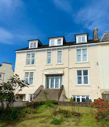 a large white house with stairs in front of it at Westbay Seafront Apartment in Oban