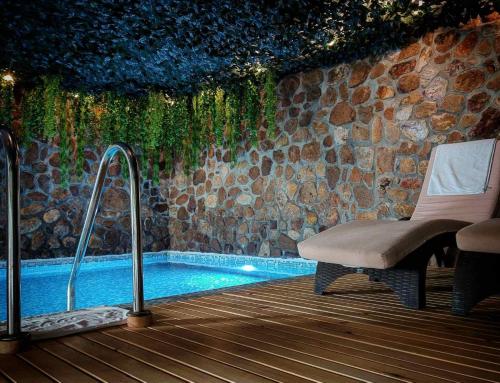 a swimming pool with a chair next to a stone wall at Aurora Resort & Spa in Berovo