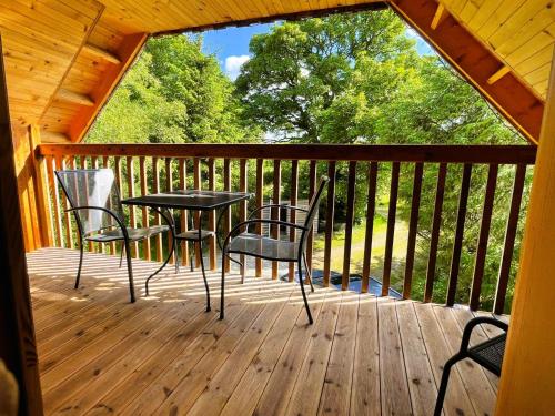 a patio with a table and chairs on a wooden deck at Deveron Valley Cottages in Marnoch