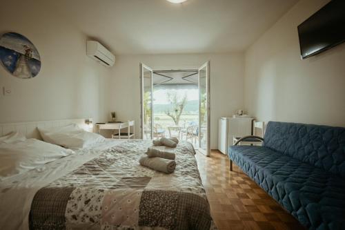 a bedroom with a bed and a blue couch at B&B Sobe Lušina in Sečovlje
